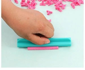 Detail of blue plastic alphabet stamper embossing pink cookie dough for DIY baking