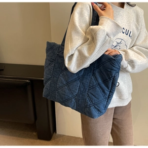 Vue détaillée du grand sac cabas matelassé en denim bleu porté par un mannequin