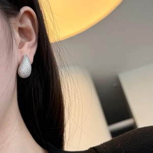 Close-up of sparkling waterdrop stud earrings with pave crystals worn on ear