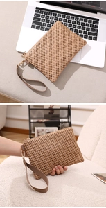 Detail showing handwoven texture and detachable wrist strap of the straw clutch bag