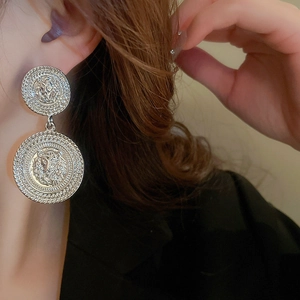 Close-up of vintage silver lion head double disk earrings with woven textured edges
