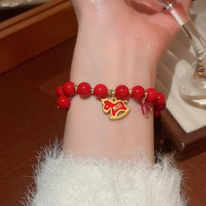 Detail of red beaded bracelet with golden horse pendant on a cozy wooden background