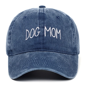 Detailed embroidery of white DOG MOM text on washed navy blue denim baseball cap surface