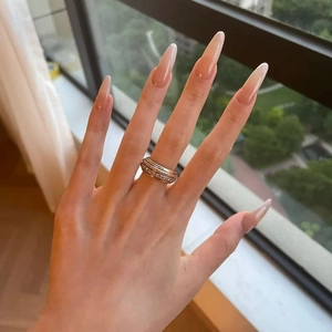 Golden wide band ring with multiple rows of pavé crystals worn on middle finger
