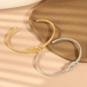 Detail von gold- und silberfarbenen Edelstahlarmbändern mit Knoten und Textur-Finish