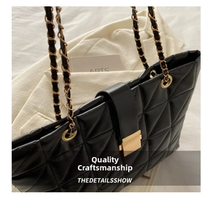 Close-up of black quilted tote bag with gold chain strap and metal clasp detail