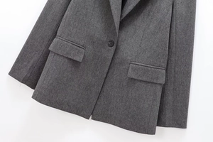 Detail of grey herringbone wool blazer showing notch lapel and classic flap pocket