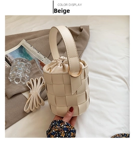 Detail of beige woven bucket bag showing wide handle and drawstring inner pouch