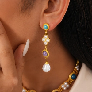 Detailed shot of vintage gold earrings with turquoise, purple gems and baroque pearls