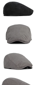 Detail view of corduroy flat caps in black and gray with side metal buckle accents