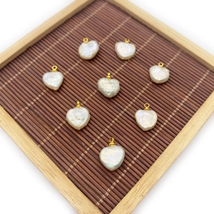 Natural heart-shaped white pearl pendants with gold rings on a bamboo tray