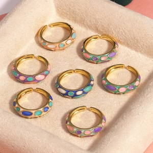 Détail de bagues ajustables en émail avec motifs colorés et finition dorée brillante