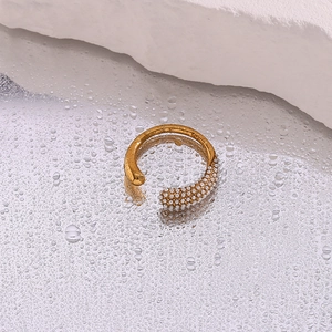 Gold open ring with teardrop pearl cluster on a reflective wet surface with rocks