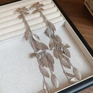Boucles d'oreilles feuilles à pampilles longues avec pendentifs mats sur velours blanc