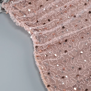 Detailed macro view of pink tulle fabric with intricate beadwork and metallic sequins