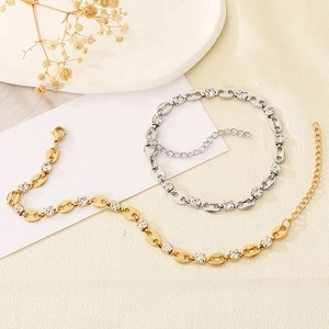 Close-up of gold and silver pig nose chain bracelets with rhinestones on silk
