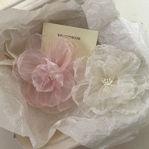 Detail of pink and white gauze camellia hair clips with pearls on crinkled paper