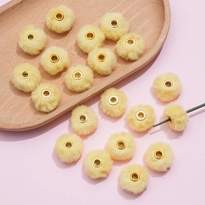 Detail of 20mm soft faux rabbit fur pompoms with gold metal eyelets for DIY crafts