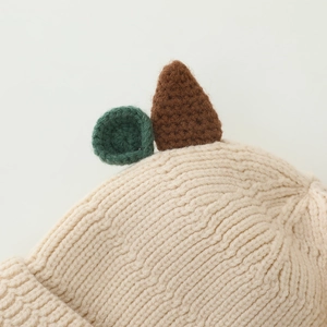 Close-up of beige knit hat featuring cute crochet horn details and textured stitching