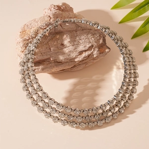 Detailed view of silver multi-layer rhinestone choker on a rock with nature accents