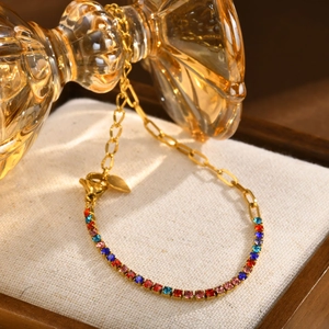 Macro shot of gold paperclip bracelet with colorful gradient cubic zirconia and heart charm