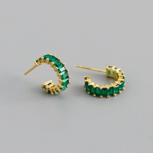 Macro view of gold S925 silver C-shaped hoop earrings with green zircon emerald cuts