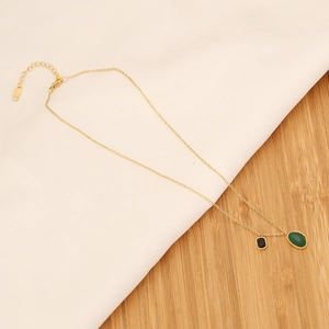 Detail of gold chain necklace with oval emerald green stone and black rectangular pendant