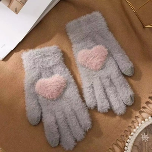 Close-up of grey plush gloves with pink heart design and touchscreen-compatible fingertips