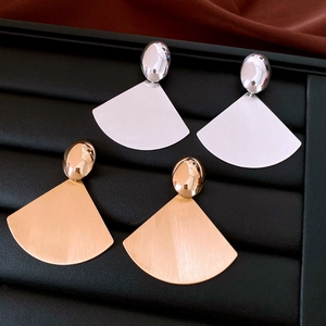 Macro detail of gold and silver fan-shaped earrings with brushed metal texture