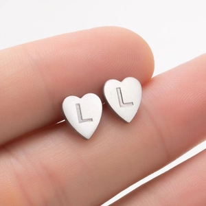 Vue macro de boucles d'oreilles cœur en argent poli avec gravure de la lettre L