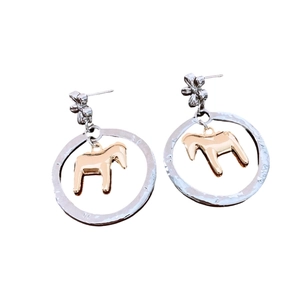 Two-tone metal hoop earrings with flower stud and golden horse pendant on white background