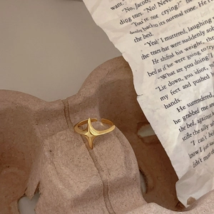 Detailed view of an adjustable gold starburst ring on a rustic textured background