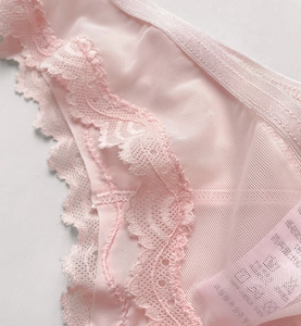 Macro shot of light pink lace edges and high-density mesh texture on sheer thong
