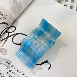 Close-up of a blue marble-patterned hair claw clip with gold glitter details and acetate finish