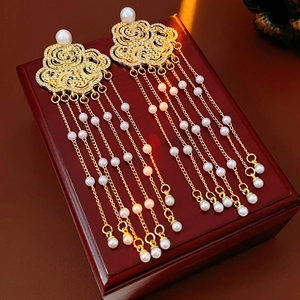Detail of gold flower earrings with pearls and crystal tassels on a red velvet box