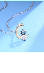 Macro shot of silver astronaut on moon pendant with blue sparkling visor detail