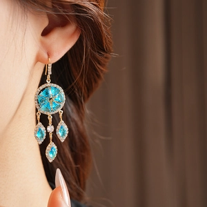 Close-up of vintage gold tassels earrings with blue crystals worn by a model