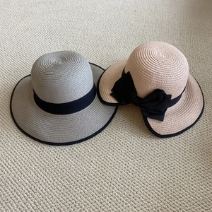 Detalle de sombreros de paja trenzada en gris y rosa con cintas decorativas negras