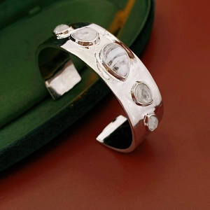 Détail d'un bracelet manchette argenté avec cinq pierres blanches sur écrin en velours