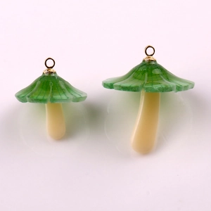 Macro detail of two green and beige mushroom pendants with golden metal hanging loops