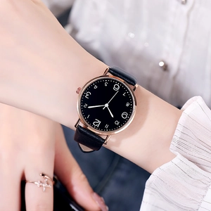 Gros plan d'une montre à quartz minimaliste à cadran noir et boîtier en or rose