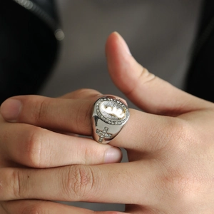Close-up of hip-hop Virgin Mary ring with side cross and pavé diamonds on finger