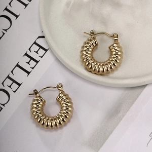 Close-up of golden stainless steel twist earrings with textured croissant design