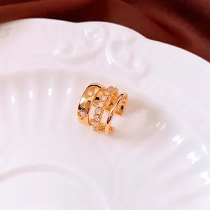 Dreilagige 18K vergoldete Ohrmanschette mit Sternengravur und Zirkonia auf einem Keramikteller