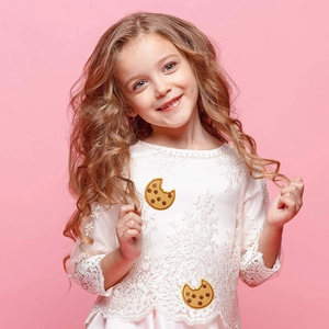 Detail of embroidered cookie patch on white lace toddler top with funny bitten design