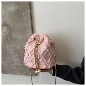 Detail of pink denim bucket bag with frayed quilted texture and gold chain strap