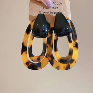 Close-up of leopard print resin earrings held against a neutral background