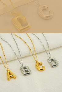Detail of gold and silver bubble letter pendants on sphere bead chains for women