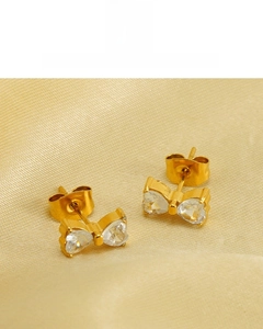 Macro view of 18K gold plated bow earrings featuring two heart-shaped cubic zirconia stones