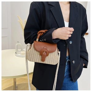 Detail of hand-woven straw crossbody bag with brown PU leather flap and rope strap